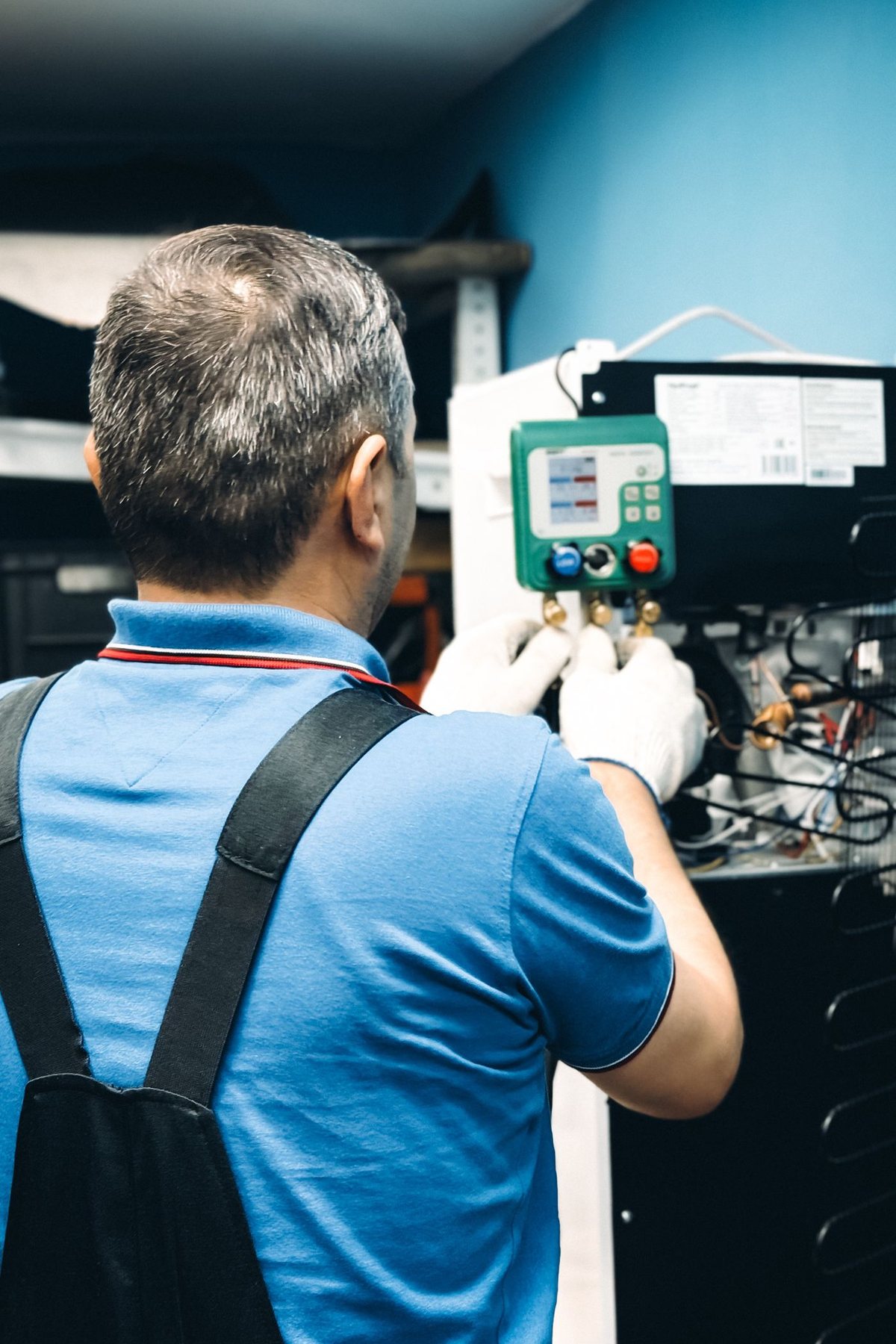 HVAC technician servicing an indoor air handler with gauges