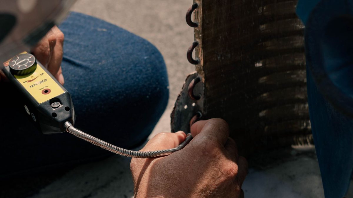 Technician cleaning and inspecting air conditioner coil fins during a tune-up