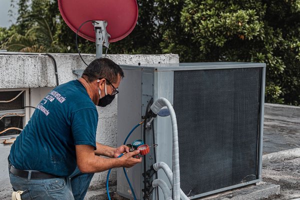 Technician servicing a rooftop air-conditioning condenser